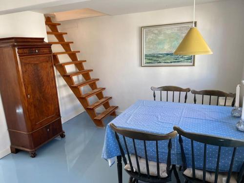 uma sala de jantar com uma mesa azul e uma escada em Skønt fiskerhus. Tæt på by, havn og havet em Marstal