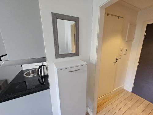 uma pequena cozinha com um lavatório e um espelho em Parkveien Comfy Studios em Oslo