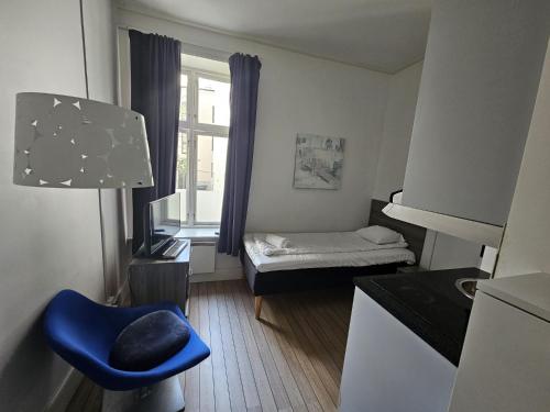 um pequeno quarto com uma cama e uma cadeira azul em Parkveien Comfy Studios em Oslo