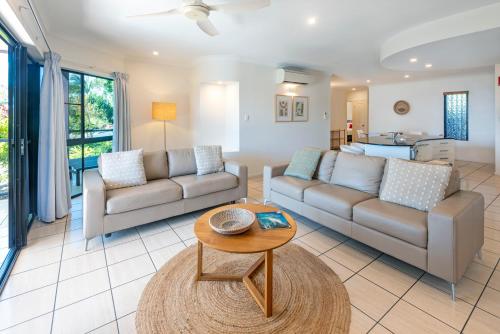 a living room with two couches and a table at Anchorage Apartments on Hamilton Island by HIHA in Hamilton Island