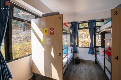 a room with two bunk beds and two windows at Zostel Rinchenpong (Pelling) in Rinchingpong
