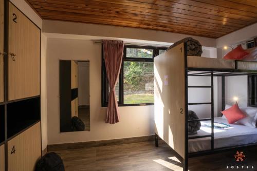 a room with two bunk beds and a window at Zostel Rinchenpong (Pelling) in Rinchingpong
