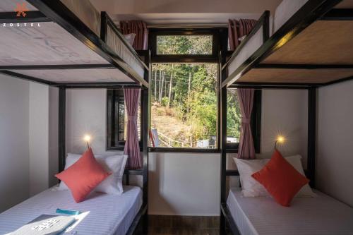 two twin beds in a room with a window at Zostel Rinchenpong (Pelling) in Rinchingpong
