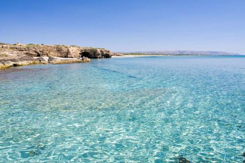 a large body of water with rocks and blue water at Suite House L'Isola Che Non C'è in Fontane Bianche