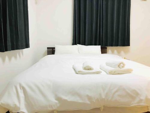 a white bed with two towels on top of it at アンドステイ島尻5丁目 in Tokyo