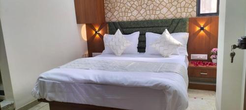艾哈邁達巴德的住宿－Hotel Gurukul INN，卧室配有一张带白色床单和枕头的大床。