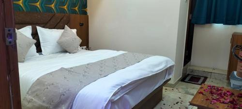 um quarto com uma cama grande e lençóis brancos em Hotel Gurukul INN em Ahmedabad