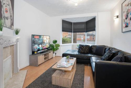 a living room with a black leather couch and a tv at 3 Bed House - 8 Guests - Parking - Top Rated -162S - Netflix - Wifi - Smart TV in Birmingham