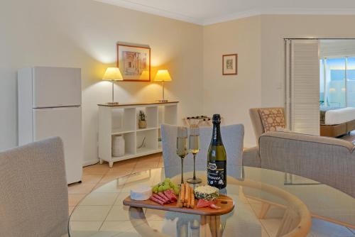 a living room with a table with a bottle of wine at The Newport on Macrossan - Adults Only in Port Douglas