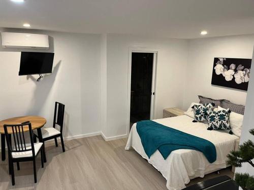 a bedroom with a bed and a table and a television at Cosy Secure comfortable for two in Canberra in Hall