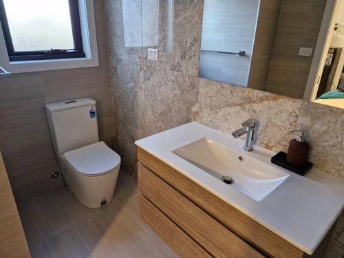 a bathroom with a white sink and a toilet at Cosy Secure comfortable for two in Canberra in Hall