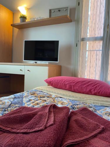- une chambre avec un lit doté d'un oreiller rouge et d'une télévision dans l'établissement Appartamento Saragozza, à Bologne