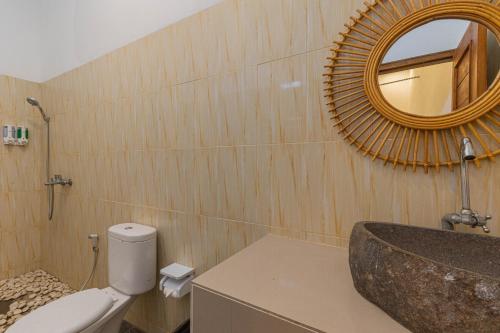 a bathroom with a sink and a toilet and a mirror at Seven Angels Villa and Hostel in Nusa Penida