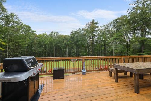 a grill and a picnic table on a wooden deck at Soose Manor Spa BBQ Games and Bar Near Lake in Tafton