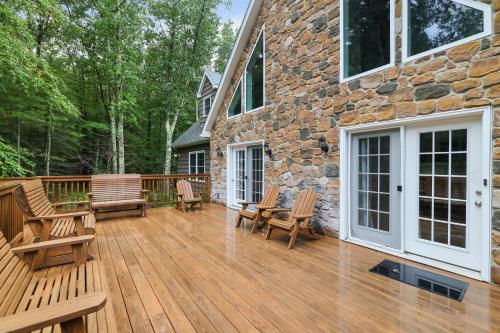 a wooden deck with chairs and a stone building at Soose Manor Spa BBQ Games and Bar Near Lake in Tafton