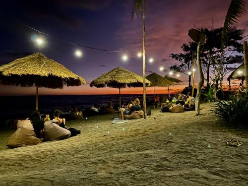 a group of people sitting under umbrellas on a beach at Uma Pantai Seseh in Canggu