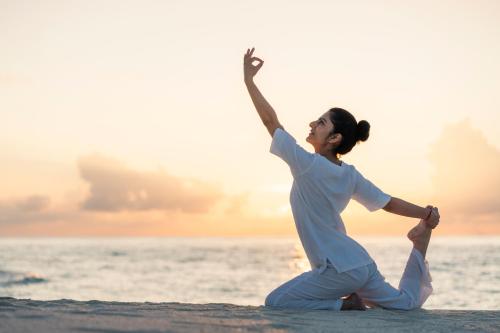 a woman doing yoga on the beach at Fushifaru Maldives with 50 percent off on sea plane roundtrip 04 nights & above in Fushifaru