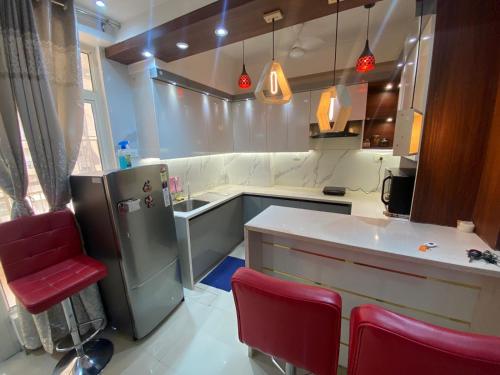 una cocina con nevera y sillas rojas. en home away from home, en Greater Noida