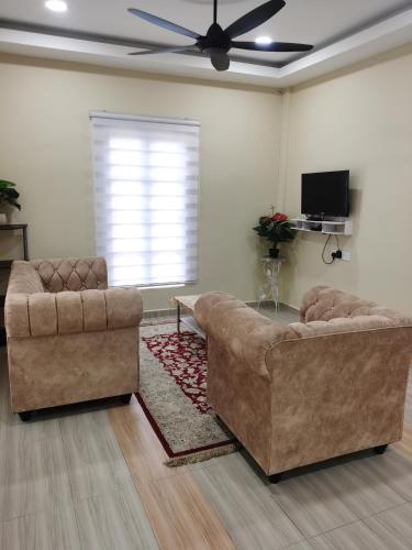 a living room with two couches and a ceiling fan at Villa Tok Wan in Kuantan