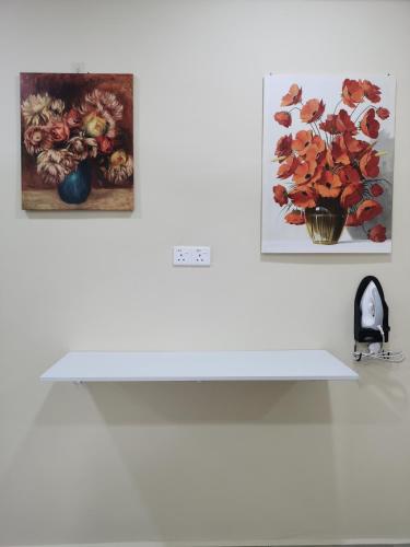 a white shelf with two paintings on a wall at Villa Tok Wan in Kuantan