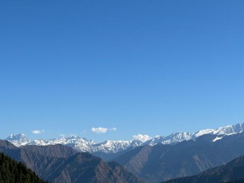 a view of a mountain range with snow covered mountains at Himalayan Canvas khajjiar in Khajjiar 