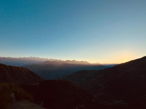 a view of a mountain range with the sun setting at Himalayan Canvas khajjiar in Khajjiar 