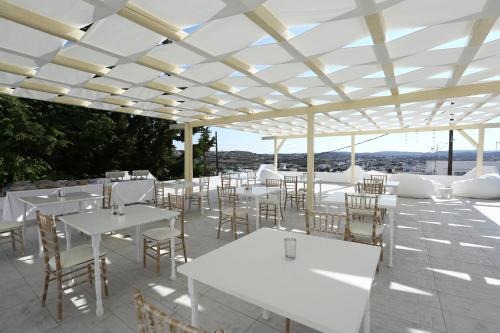 a restaurant with white tables and chairs on a patio at The White Suites in Adamas