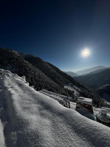 a snow covered mountain with the moon in the sky at Himalayan Canvas khajjiar in Khajjiar 