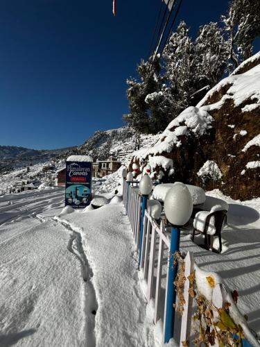 a fence covered in snow next to a road at Himalayan Canvas khajjiar in Khajjiar 