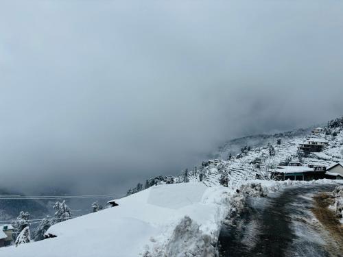 a snow covered hill with houses on a mountain at Himalayan Canvas khajjiar in Khajjiar 