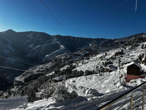 a snow covered mountain with a ski lodge on it at Himalayan Canvas khajjiar in Khajjiar 