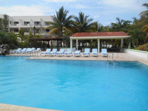 a large swimming pool with chairs and a gazebo at Hotel Club Akumal Caribe in Akumal
