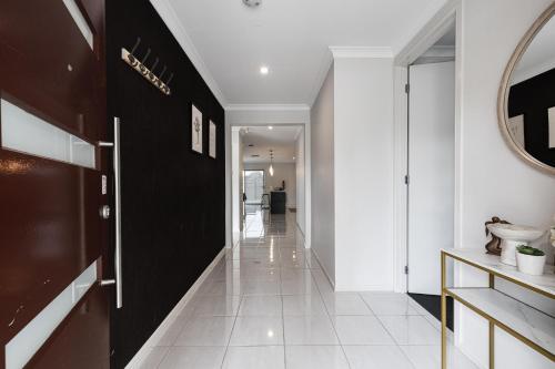 un pasillo con paredes blancas y negras y suelo de baldosa blanca en Modern 4BR house perfect for family getaway, en Point Cook