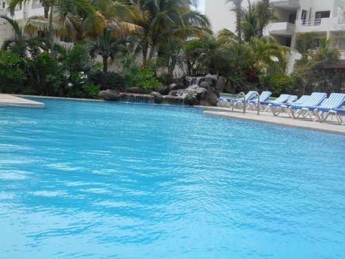 a large blue swimming pool with chairs and palm trees at Hotel Club Akumal Caribe in Akumal