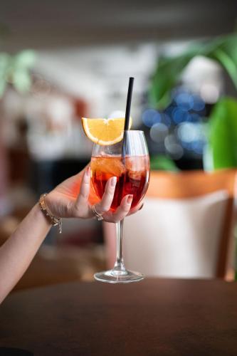 a person holding a drink with an orange slice at Charme Hotel in Prato