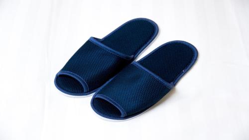two black flip flops sitting on a white background at Dormy Inn Express Kakegawa in Kakegawa