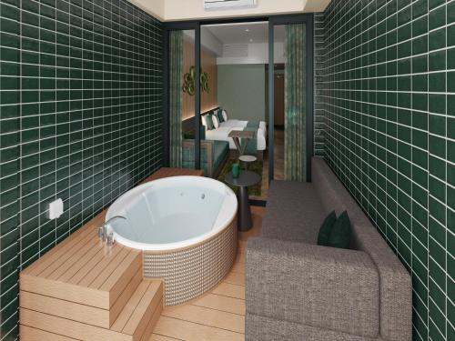 TWIN LINE HOTEL YANBARU OKINAWA JAPAN Formerly Okinawa Suncoast Hotel في ناغُو: حمام مع حوض استحمام ومقعد وطاولة