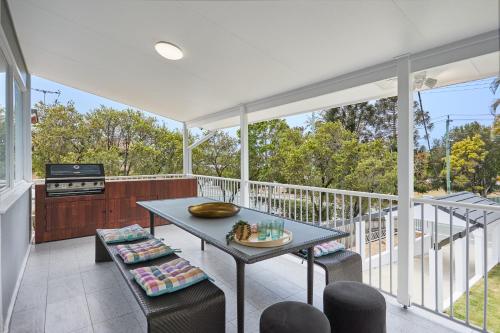 a screened in porch with a table and chairs at The Queenslander! Complete Entertainer - Huge - Stylish - Games - Full Level Pool Room - Smokehouse - Secure Parking - Yard #NEW! in Gold Coast