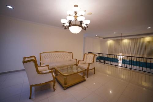 a room with two chairs and a table and a chandelier at Noola Inn Hotel Bogor in Kamparganya