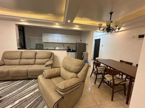 a living room with couches and a table and a kitchen at Home Croft Nairobi in Nairobi