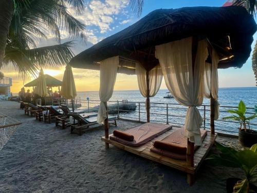 a group of beds on a beach with the ocean at The Philip Ann Resort in Mabini