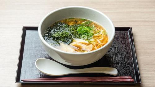 a bowl of soup on a plate with a spoon at Dormy Inn Express Kakegawa in Kakegawa
