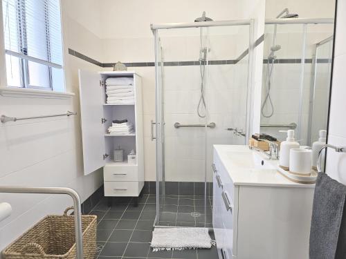 a white bathroom with a shower and a sink at New: Araluen, Heart of Bowral in Bowral