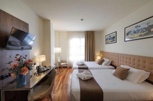 a hotel room with two beds and a flat screen tv at Charme Hotel in Prato