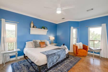 een blauwe slaapkamer met een bed en een oranje stoel bij The Outlook - Spa and deck views of Hill Country in Dripping Springs