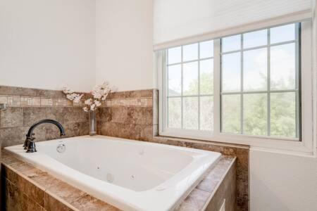 a large bath tub in a bathroom with a window at The Outlook - Spa and deck views of Hill Country in Dripping Springs