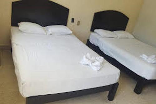 two beds in a hotel room with white sheets at HOTEL PALACIO in Acapulco