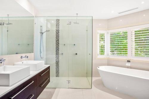 La salle de bains est pourvue de 2 lavabos, d'une baignoire et d'une douche. dans l'établissement Mermaid Waters House, à Gold Coast