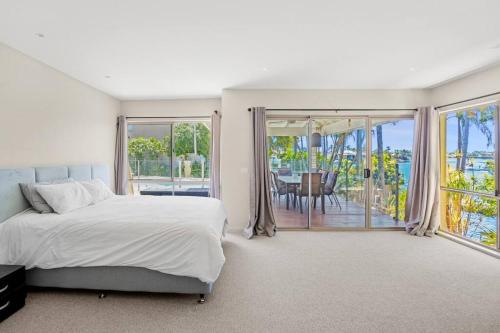 a white bedroom with a bed and a balcony at Mermaid Waters House in Gold Coast