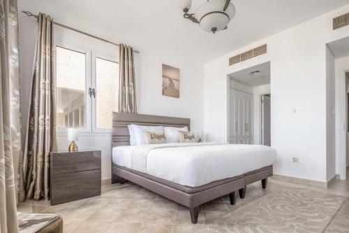 a white bedroom with a large bed and a window at Frank Porter - Al Badia 2 in Dubai
